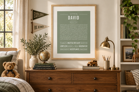 Framed sage green David Name Stories® art print displayed in a warm, timeless boy’s room with natural wood, books, greenery and vintage-inspired decor.
