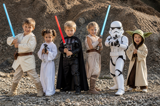Children dressed in Star Wars-inspired costumes posing outdoors with toy lightsabers, including Jedi, princess, and stormtrooper outfits.