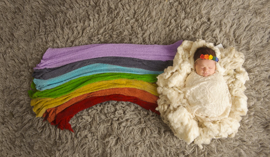 Photo of a baby with flowing rainbow colored material