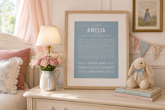 Framed Amelia Name Stories® art print in a soft blue design displayed in an elegant blush-and-blue nursery with flowers, books, and vintage decor.