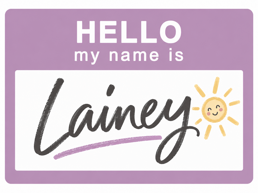 Lavender “Hello, My Name Is” name tag featuring Lainey in charcoal handwritten lettering with a smiling sunshine doodle, celebrating the cheerful girl's name meaning “ray of light.”