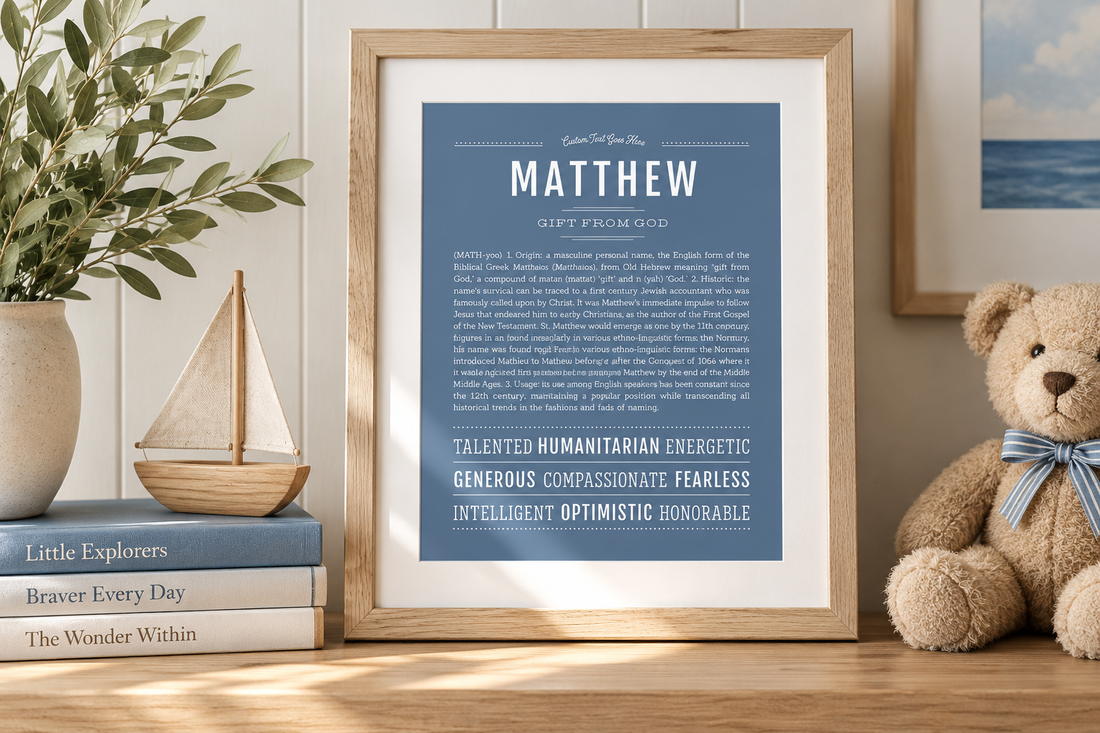 Framed blue Matthew Name Stories® art print displayed in a warm, coastal-inspired nursery with a wooden sailboat, teddy bear and greenery.