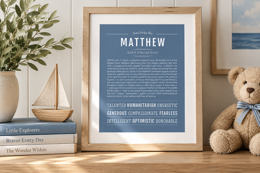 Framed blue Matthew Name Stories® art print displayed in a warm, coastal-inspired nursery with a wooden sailboat, teddy bear and greenery.